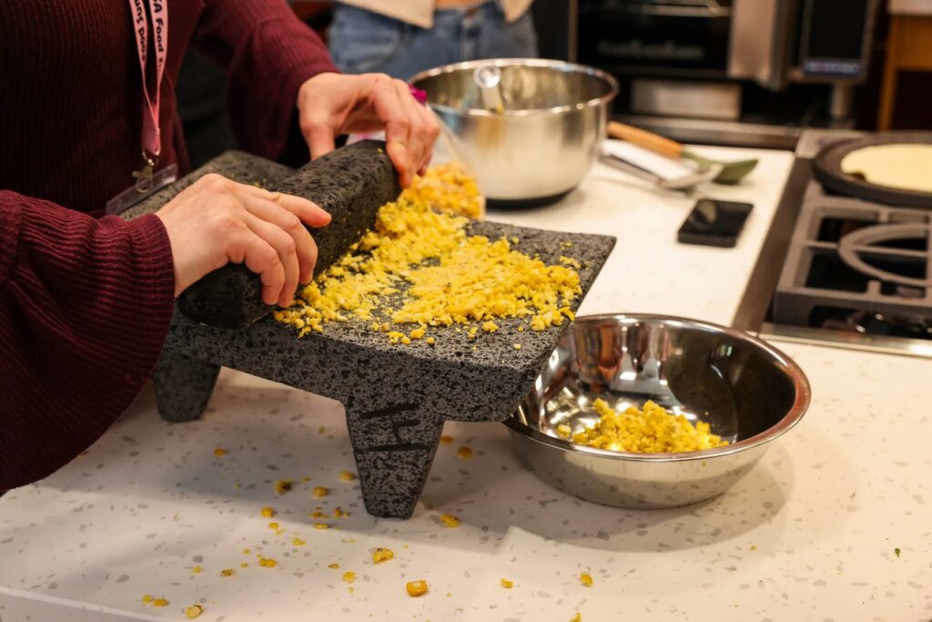 A summit attendee grinds corn for fresh tortillas during a teaching kitchen class that took place during the Indigenous Food Summit at Portland State University on September 9, 2026. (Photo by Nika Bartoo-Smith, Underscore Native News / ICT)